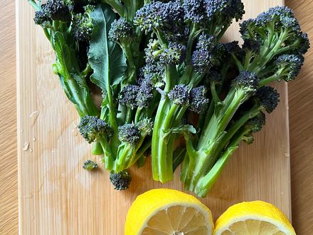 Fresh purple sprouting broccoli and lemons on a board