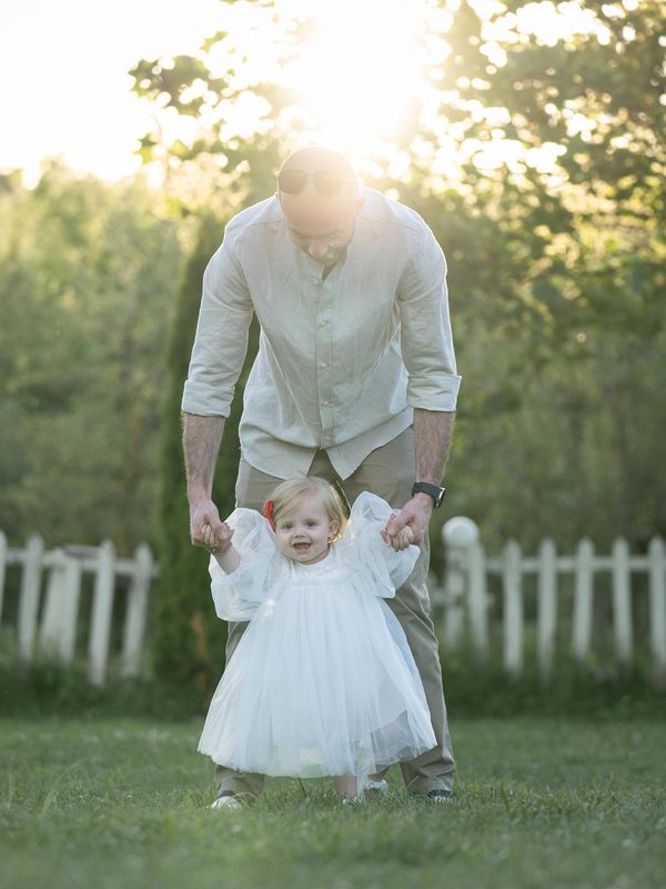 A father helping his toddler walk in the garden